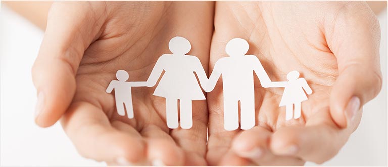 Hands holding paper cutout of stick figure family